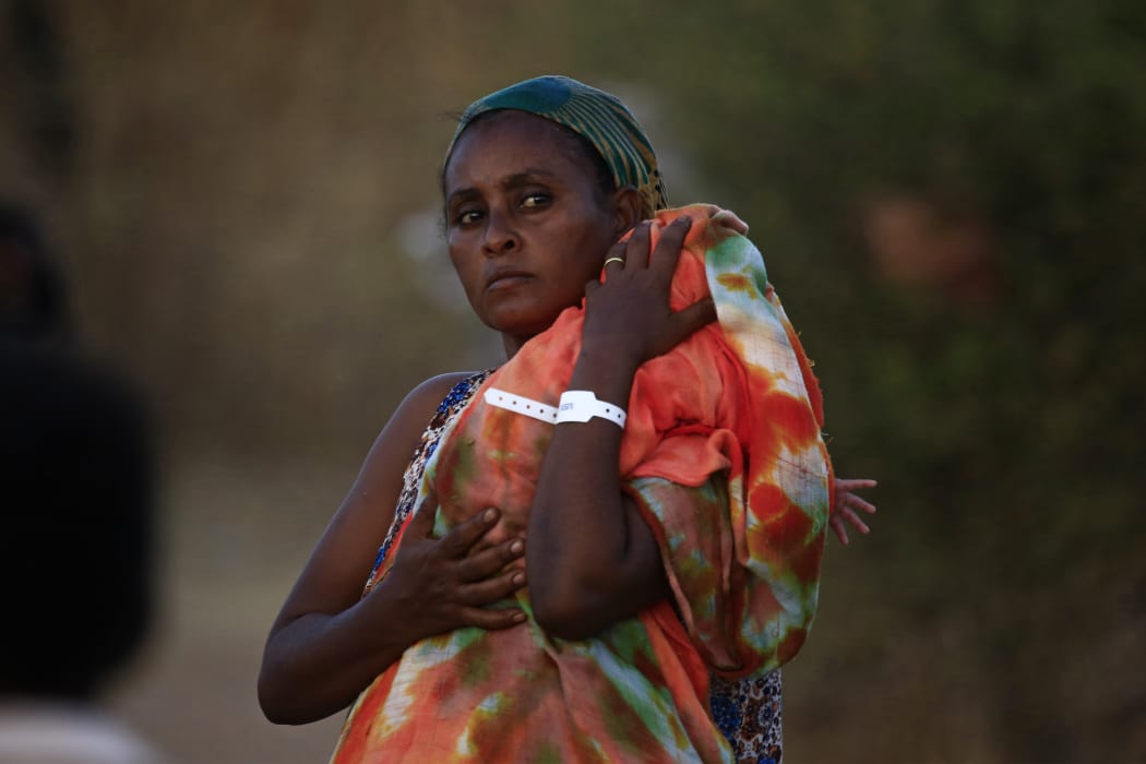 An Ethiopian refugee who fled fighting in Tigray province carries her baby as she walks at the Um Rakuba camp in Sudan's eastern Gedaref province, on November 21, 2020.