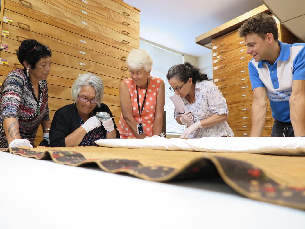 Kahutoi Te Kanawa, Te Hemo Ata Henare, Maureen Lander, Lisa McKendry and Charlie Charlick closely observing the (poka) shaping of a kaitaka (cloak).
