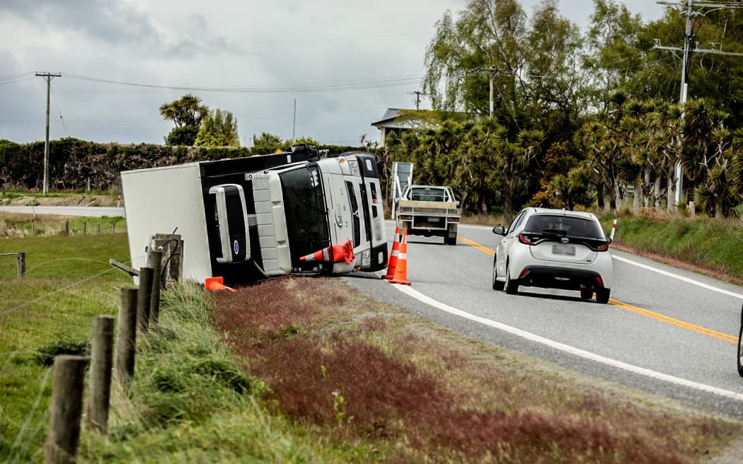 Two refrigerated trucks lay on their sides after toppling on an exposed part of SH1 just outside of Balclutha