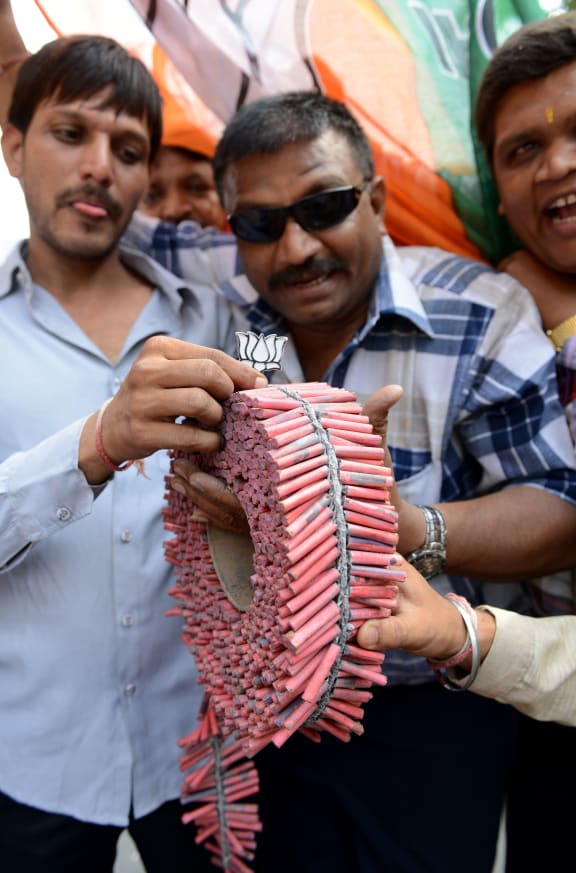 Supporters of the Bhartiya Janta Party (BJP) display the party's symbol, the 'Lotus' flower on a roll of firecrackers as they celebrate victory .