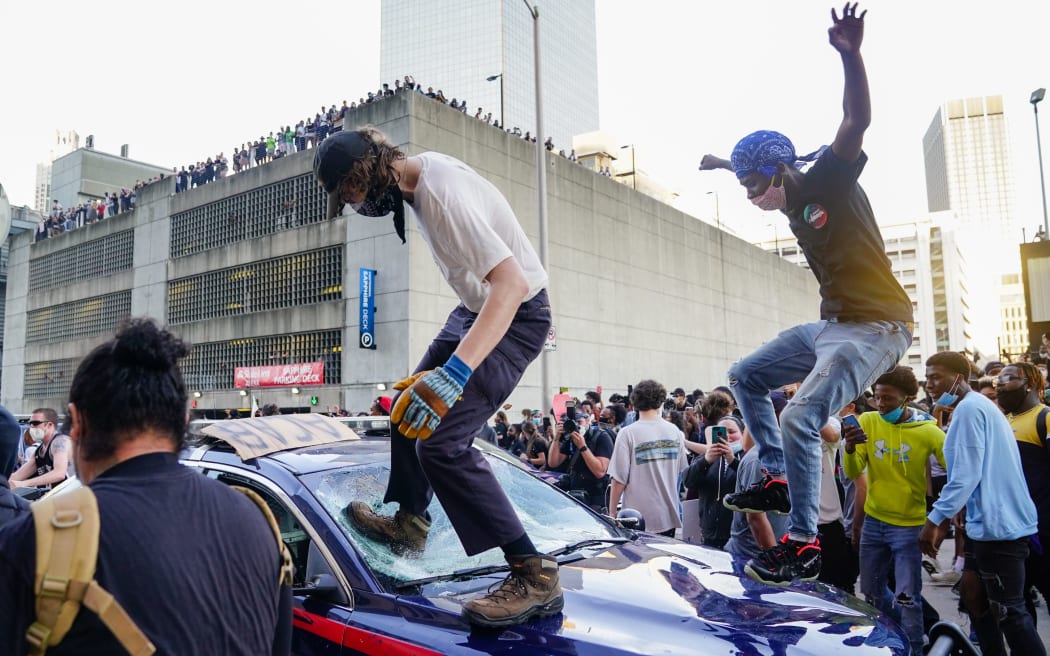 ATLANTA, GA - MAY 29: Protesters smash a police car during a protest outside CNN Center on May 29, 2020 in Atlanta, Georgia.