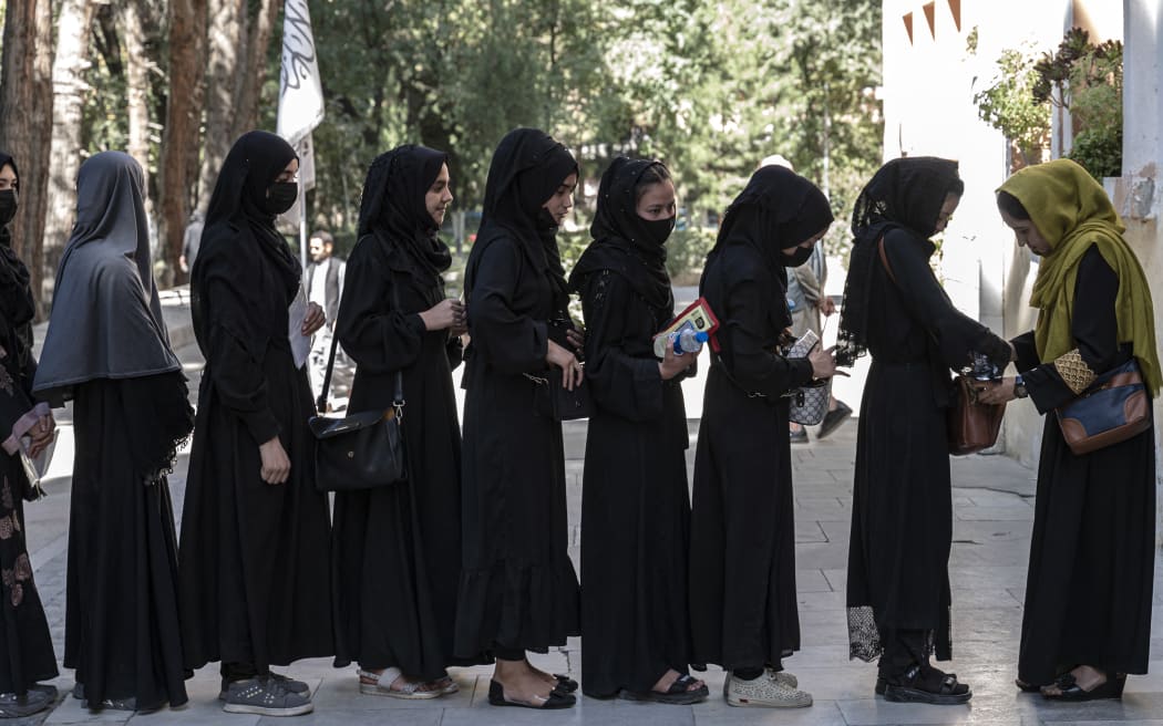 An Afghan female guard frisks students before they sit for entrance exams at the Kabul University in Kabul on 13 October, 2022.