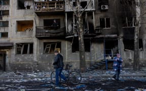 People walk by a damaged residential building following a strike in Dobropillia, Donetsk region, on March 8, 2025, amid the Russian invasion of Ukraine. At least 11 people were killed and 30 wounded in Russian strikes on eastern Ukraine's Donetsk region late March 7, the country's emergency service said, raising the earlier death toll of four. "In the evening, Russians struck the centre of Dobropillia. At least 11 people were killed and 30 others were wounded," the service wrote in a post on Telegram, adding that at least nine buildings were damaged. (Photo by Tetiana DZHAFAROVA / AFP)