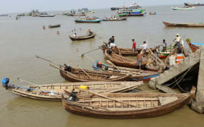 Local craft tie up to concrete steps with men also in the calm but dirty water