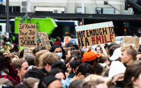 Signs visible as the crowd marches in Auckland.