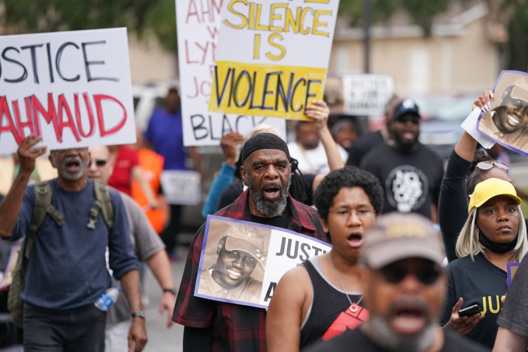 Demonstrators march near the Glynn County Courthouse where the trial for the killers of Ahmaud Arbery is taking place.