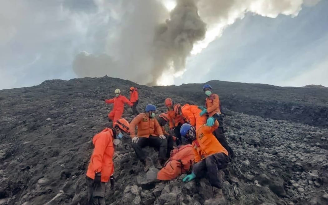 This handout photo taken on December 4, 2023 and released on December 5, 2023 by the National Search and Rescue Agency (BASARNAS) shows rescuers evacuating one of the victims from the slopes of Mount Marapi in West Sumatra. Hundreds of Indonesian rescuers were racing on December 5 to find 10 hikers who went missing after a volcano eruption that killed 13 people. (Photo by Handout / BASARNAS / AFP) / RESTRICTED TO EDITORIAL USE - MANDATORY CREDIT "AFP PHOTO / National Search and Rescue Agency (BASARNAS)" - NO MARKETING - NO ADVERTISING CAMPAIGNS - DISTRIBUTED AS A SERVICE TO CLIENTS