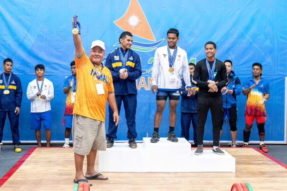 Marshall Islands weightlifter Patterson Raymon River at the podium (white shirt) is recognized by Majol2024 Micro Games Chairman Tony Muller for winning two gold medals and one silver medal Monday this week. Photo: Chewy Lin.