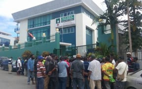 A crowd gathers outside the headquarters of PNG's electoral commission as news spreads of the arrest of senior officials.