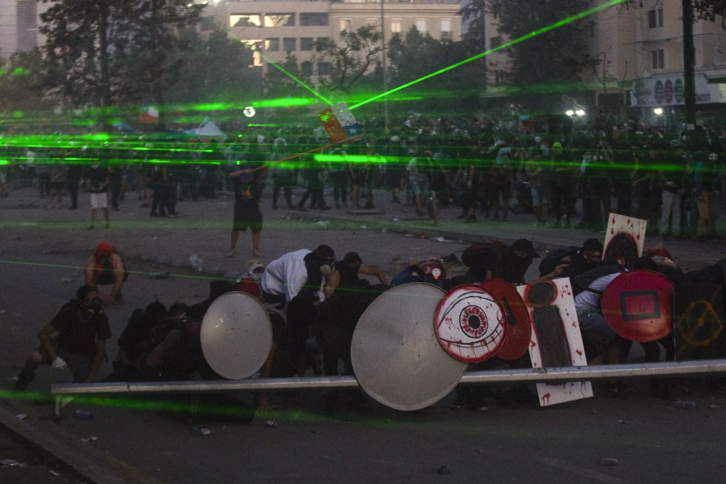 Demonstrators clash with riot police during a protest in Santiago on Friday. The announced the same day it will stage a referendum to replace the country's dictatorship-era constitution - a key demand of protesters after nearly a month of civil unrest.