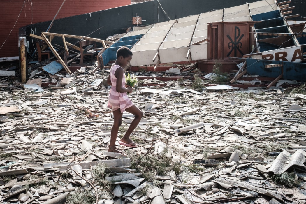 A girl collects artificial flowers from the rubble of a building destroyed by the cyclone Idai at Sacred Heart Catholic Church in Beira, Mozambique.