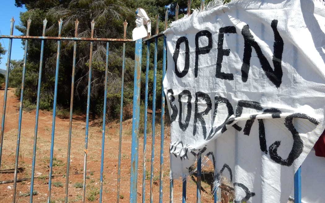 A sign saying "open borders" hangs at the entrance to Ritsona refugee camp.