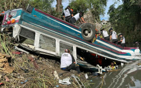Volunteer firefighters work at the scene of an accident in which a bus fell down a ravine in Guatemala City on February 10, 2025. A bus carrying 75 people plunged into a ravine in Guatemala City on Monday, killing at least 31 people, rescue workers said. (Photo by Johan ORDONEZ / AFP)