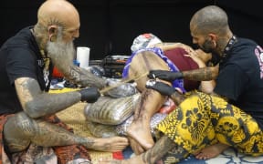 Former Auckland tattooist Brent McCown, (left) and his colleague Smiley Dogg, from Mallorca, create a tattoo using traditional Samoan techniques at the NZ Tattoo and Art Festival in New Plymouth.