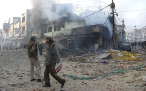 Police officers in front of vandalised shops following clashes between supporters and opponents of a new citizenship law, at Bhajanpura area of New Delhi.