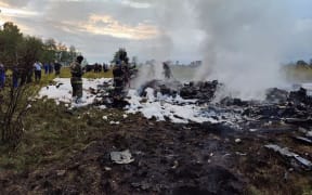 A handout photograph taken and released by Russian Investigative Committee on August 23, 2023, shows rescuers working at the site of a plane crash near the village of Kuzhenkino, Tver region.