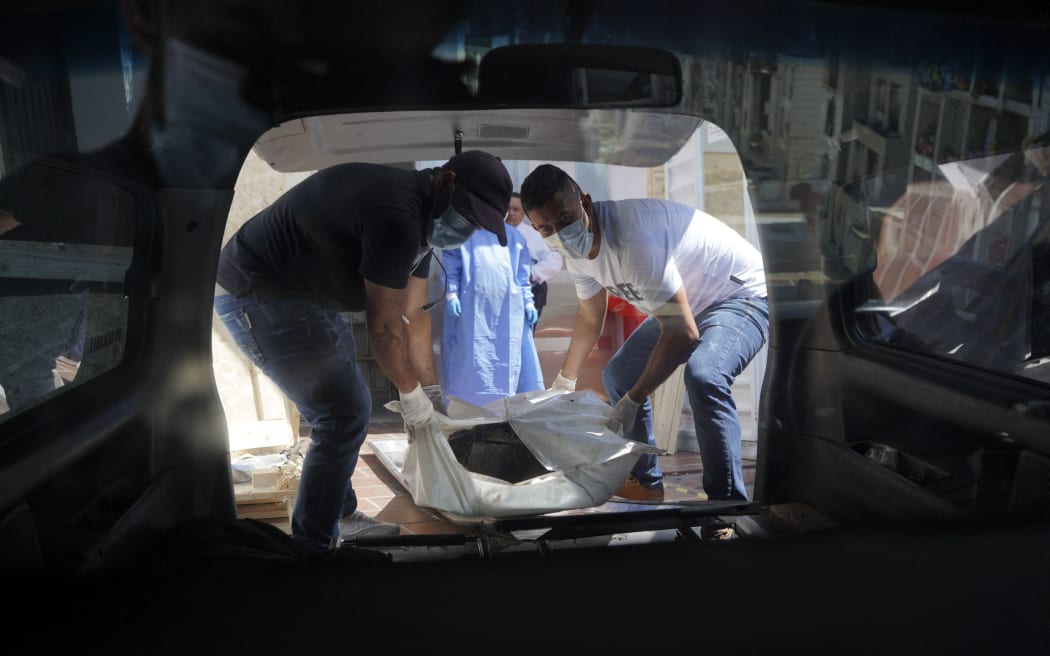 Funeral workers carry the corpse of a victim of clashes between armed leftist groups taking place in the Catatumbo region in Cucuta, Norte de Santander department, Colombia, on January 23, 2025. Colombia is battling its worst security crisis in a decade after a series of guerrilla attacks in the north of the country have left at least 80 people dead and displaced 36,000 others. (Photo by YEISON PICON / AFP)
