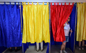 A woman leaves one of the voting booths with curtains in the colors of Romania as she prepares to cast her vote during European Parliament Elections at a polling station in Bucharest, Romania, on June 9, 2024.