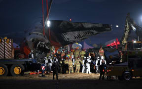 Firefighters and rescue personnel carry the body of a victim near the scene where a Jeju Air Boeing 737-800 series aircraft crashed and burst into flames at Muan International Airport in South Jeolla Province, some 288 kilometres southwest of Seoul on December 29, 2024. - A Jeju Air plane carrying 181 people from Thailand to South Korea crashed on arrival, smashing into a barrier and bursting into flames, leaving all but two feared dead.