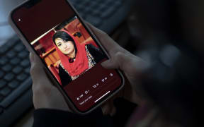 A woman looks at a picture of former Afghan MP Mursal Nabizada on her mobile phone. Nabizada and one of her bodyguards were shot dead by gunmen at her house in Kabul last night.