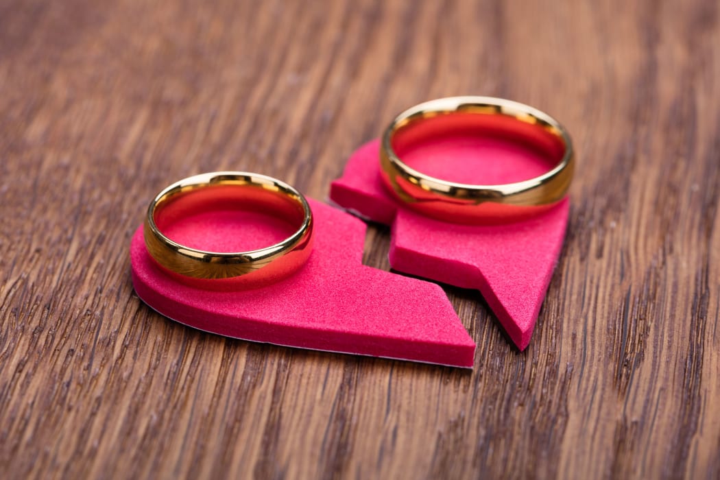 69590501 - high angle view of golden ring on red broken heart at wooden desk
