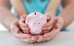 A man and a child hold a piggy bank