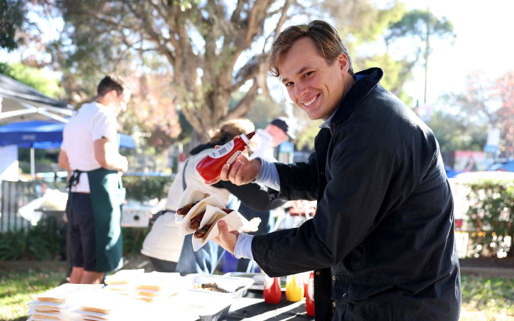 A voter enjoys a sausage, known informally as "democracy sausages", during Australia’s general election at a polling station in Melbourne on May 3, 2025. (Photo by Martin KEEP / AFP)
