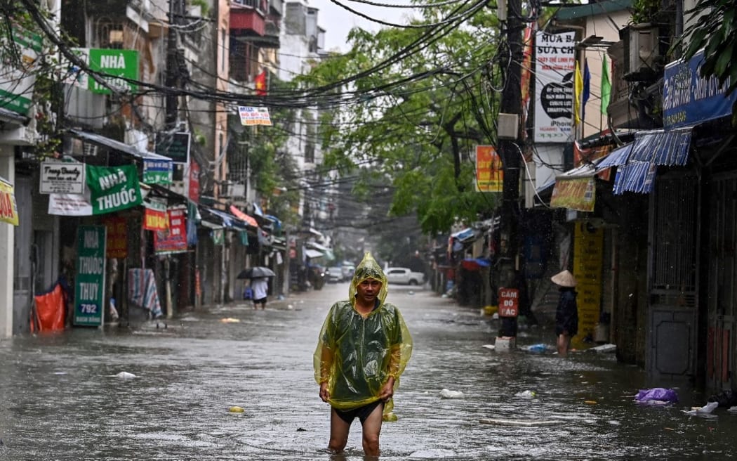 A man wearing a plastic poncho wades through flood waters on a street in Hanoi on September 11, 2024, as heavy rains in the aftermath of Typhoon Yagi brought flooding to northern Vietnam. Residents of Hanoi waded through waist-deep water on September 11 as river levels hit a 20-year high and the toll from the strongest typhoon in decades passed 150, with neighbouring nations also enduring deadly flooding and landslides. (Photo by Nhac NGUYEN / AFP)