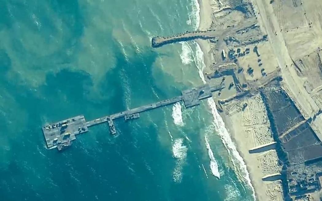 This handout picture courtesy of the US Central Command (CENTCOM) taken on May 16, 2024 shows US Army Soldiers assigned to the 7th Transportation Brigade (Expeditionary), US Navy Sailors assigned to Amphibious Construction Battalion 1, and Israel Defense Forces emplace the Trident Pier on the Gaza coast. The US military said aid deliveries began May 17, 2024 via a temporary pier in Gaza aimed at ramping up emergency humanitarian assistance to the war-ravaged Palestinian territory. (Photo by US Central Command (CENTCOM) / AFP) / RESTRICTED TO EDITORIAL USE - MANDATORY CREDIT "AFP PHOTO / US Central Command (CENTOCOM)" - NO MARKETING NO ADVERTISING CAMPAIGNS - DISTRIBUTED AS A SERVICE TO CLIENTS