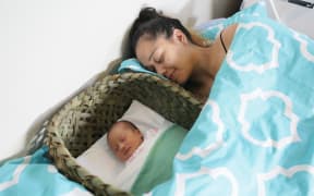 Aniwa Pitman-Clark with six-day-old Jypsy-Rain Pitman Martin sleeping safely in her wahakura.