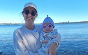Melanie Connell holding a baby at a beach.