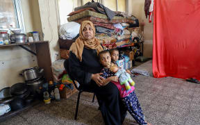 A displaced Palestinian woman with her children at a schoolroom in the Jabalia Refugee Camp, northern Gaza, 5 May 2024.