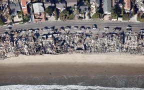 MALIBU, CALIFORNIA - JANUARY 13: An aerial view shows utility vehicles parked near homes destroyed in the Palisades Fire as wildfires cause damage and loss through the LA region on January 13, 2025 in Malibu, California. Multiple wildfires fueled by intense Santa Ana Winds continue to burn across Los Angeles County, with some containment achieved. According to reports, 24 people have died with over 180,000 people under evacuation order or warning. Over 12,000 structures have been destroyed or damaged, while more than 35,000 acres have burned.   Mario Tama/Getty Images/AFP (Photo by MARIO TAMA / GETTY IMAGES NORTH AMERICA / Getty Images via AFP)