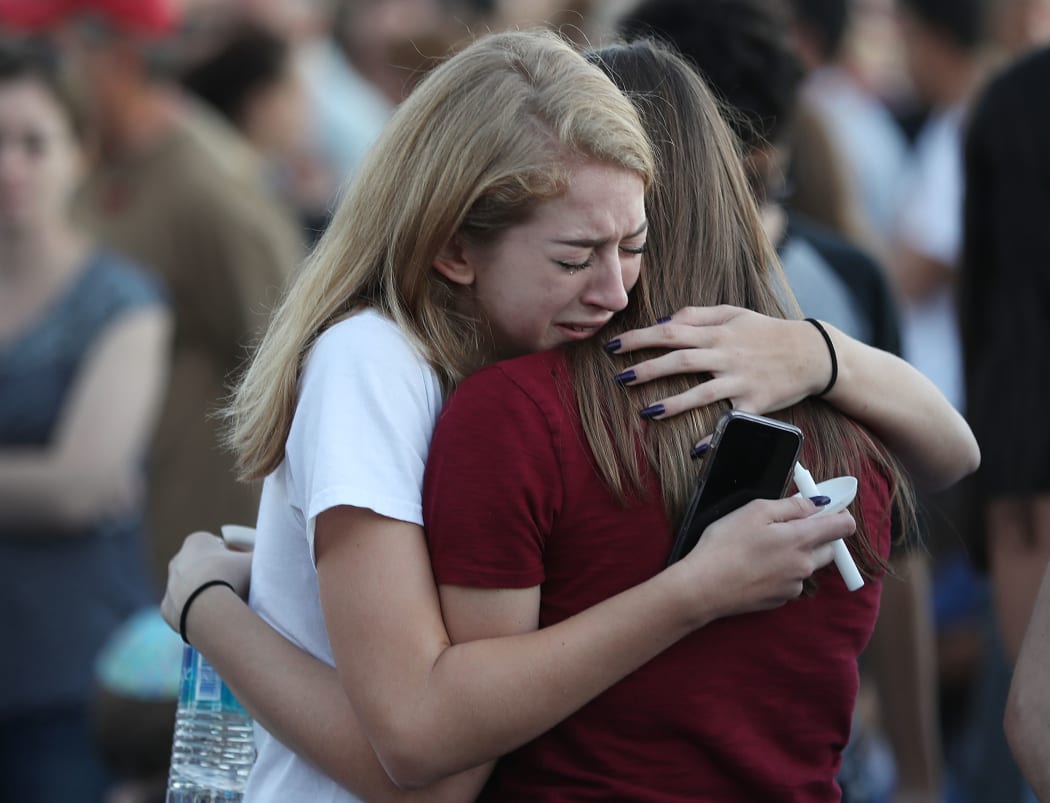 People hug as they attend a candlelight memorial service for the victims of the shooting at Marjory Stoneman Douglas High School that killed 17 people on February 15, 2018 in Parkland, Florida.