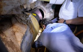 New York Governor Andrew Cuomo inspects a pipe cut open in the escape - a note on yellow paper left by the fugitives can also be seen.