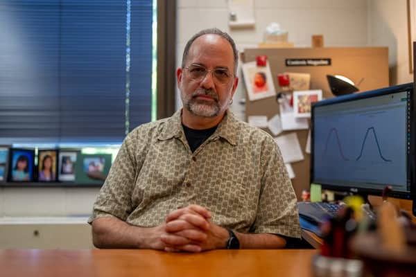 Philip Cohen sits on his desk with his hands clasped.