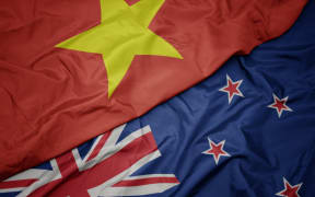 waving colorful flag of new zealand and national flag of vietnam. macro