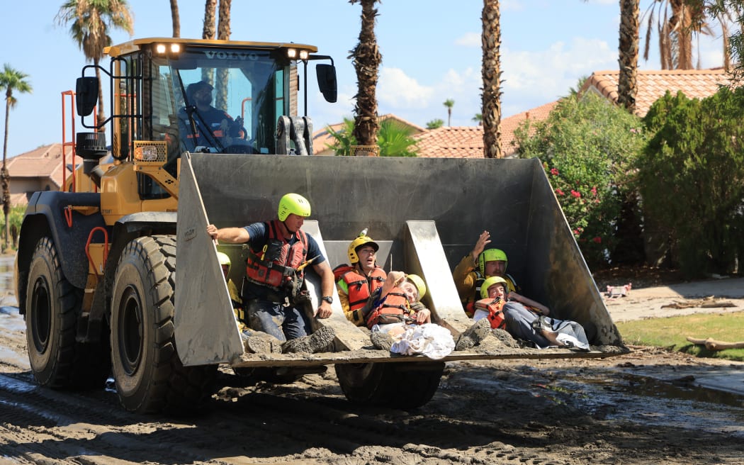 Members of the Cathedral City Fire Department rescue residents in a bulldozer following heavy rains from Tropical Storm Hilary in Cathedral City, California, on August 21, 2023. Tropical Storm Hilary drenched Southern California with record rainfall, shutting down schools, roads and businesses before edging in on Nevada on August 21, 2023. California Governor Gavin Newsom had declared a state of emergency over much of the typically dry area, where flash flood warnings remained in effect until this morning.