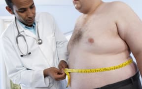 Doctor measuring the waist of an obese patient.