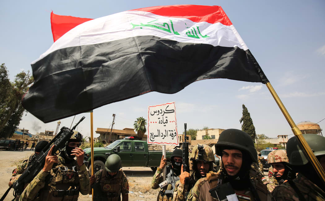 Members of the Iraqi federal police wave national flags during a military parade as they celebrate in the Old City of Mosul, where the gruelling battle to retake Iraq's second city from Islamic State (IS) group fighters is now nearing its end, on July 2, 2017.