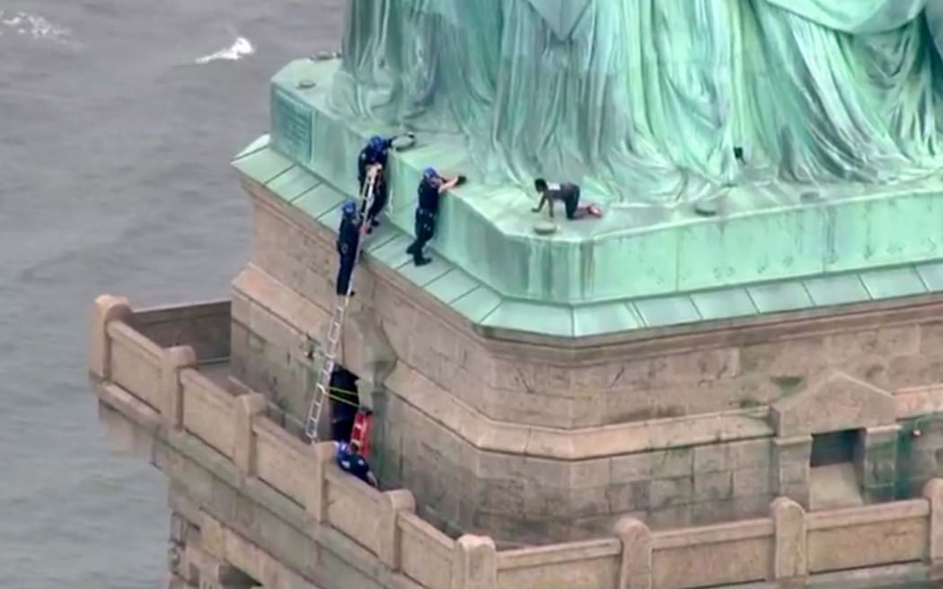 Police talk to a woman who climbed to the base of the Statue of Liberty.