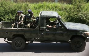 Military personnel sit aboard a vehicle driving in Bujumbura on December 11, 2015.