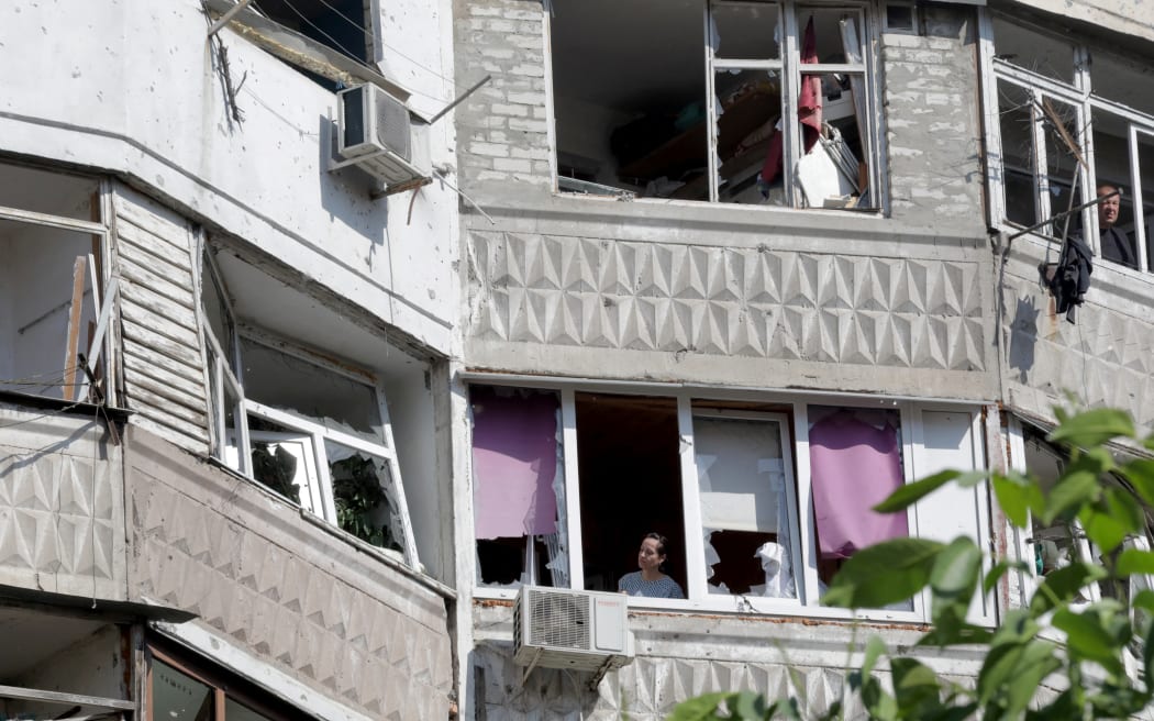 Residents watch from their windows in a damaged residential building after a Russian drone attack in the Ukrainian Black Sea city of Odessa on June 10, 2023, amid the Russian invasion of Ukraine. At least three people were killed early on June 10, 2023 in a fire sparked by falling debris from shot-down drones in the region of Odesa in southern Ukraine, regional officials said. (Photo by Oleksandr GIMANOV / AFP)