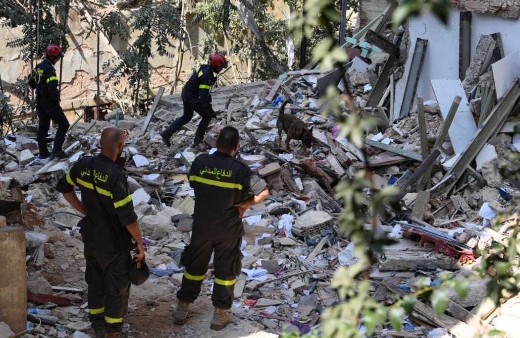 Members of the Lebanese civil defence look on as French rescuers use a dog to search for victims and survivors amidst the rubble of a building in the Gemayzeh neighbourhood on August 6, 2020, two days after a massive explosion in the Beirut port shook the capital.