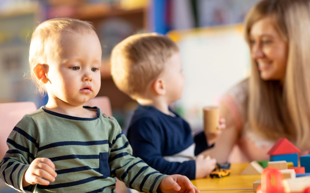 Nursery babies playing blocks toy with teacher in kindergarten