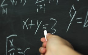 A teacher uses a blackboard to solve a mathematics equation.