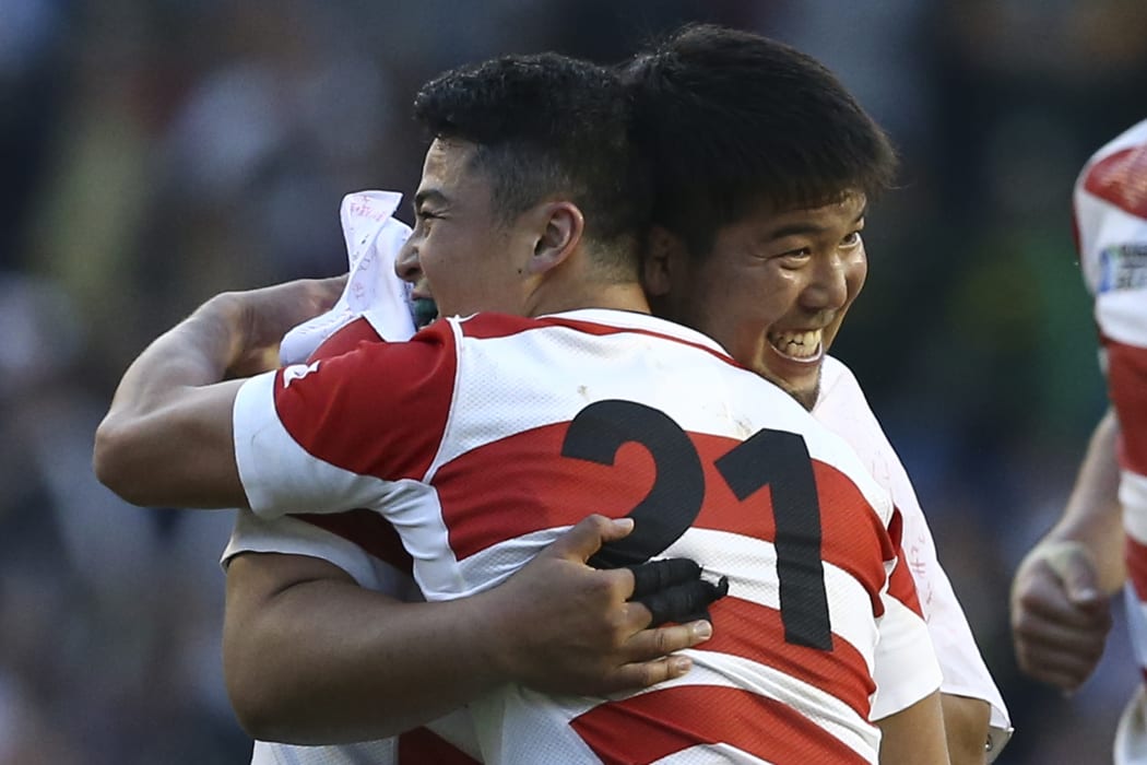 Japan's prop Kensuke Hatakeyama (L) embraces Japan's scrum half Atsushi Hiwasa (R) after winning the Pool B match of the 2015 Rugby World Cup with South Africa.