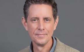 Relaxed smile portrait of Wallace Chapman on grey background