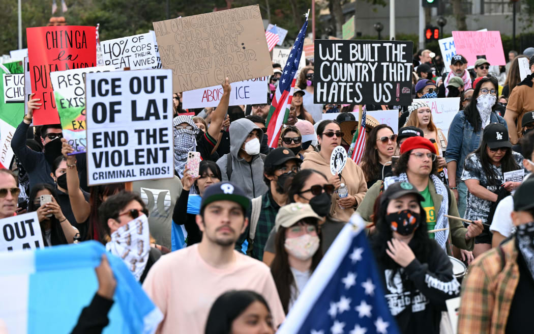 Protesters hold up signs as they gather to demonstrate against federal immigration operations at Pershing Square in downtown Los Angeles, on June 11, 2025. Protests against Donald Trump's harsh immigration policies spread on June 11 across the United States despite a military-backed crackdown in Los Angeles and threats by the hard-right Republican president to use "heavy force." In Los Angeles, where the unrest began on June 6, an overnight curfew intended to keep people out of the downtown area was largely effective, with police arresting around 25 people who had refused to leave. (Photo by RONALDO SCHEMIDT / AFP)