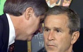 White House Chief of Staff Andy Card tells US President George W. Bush about the terror attack on the World Trade Center, while Bush is reading to children at a school visit.